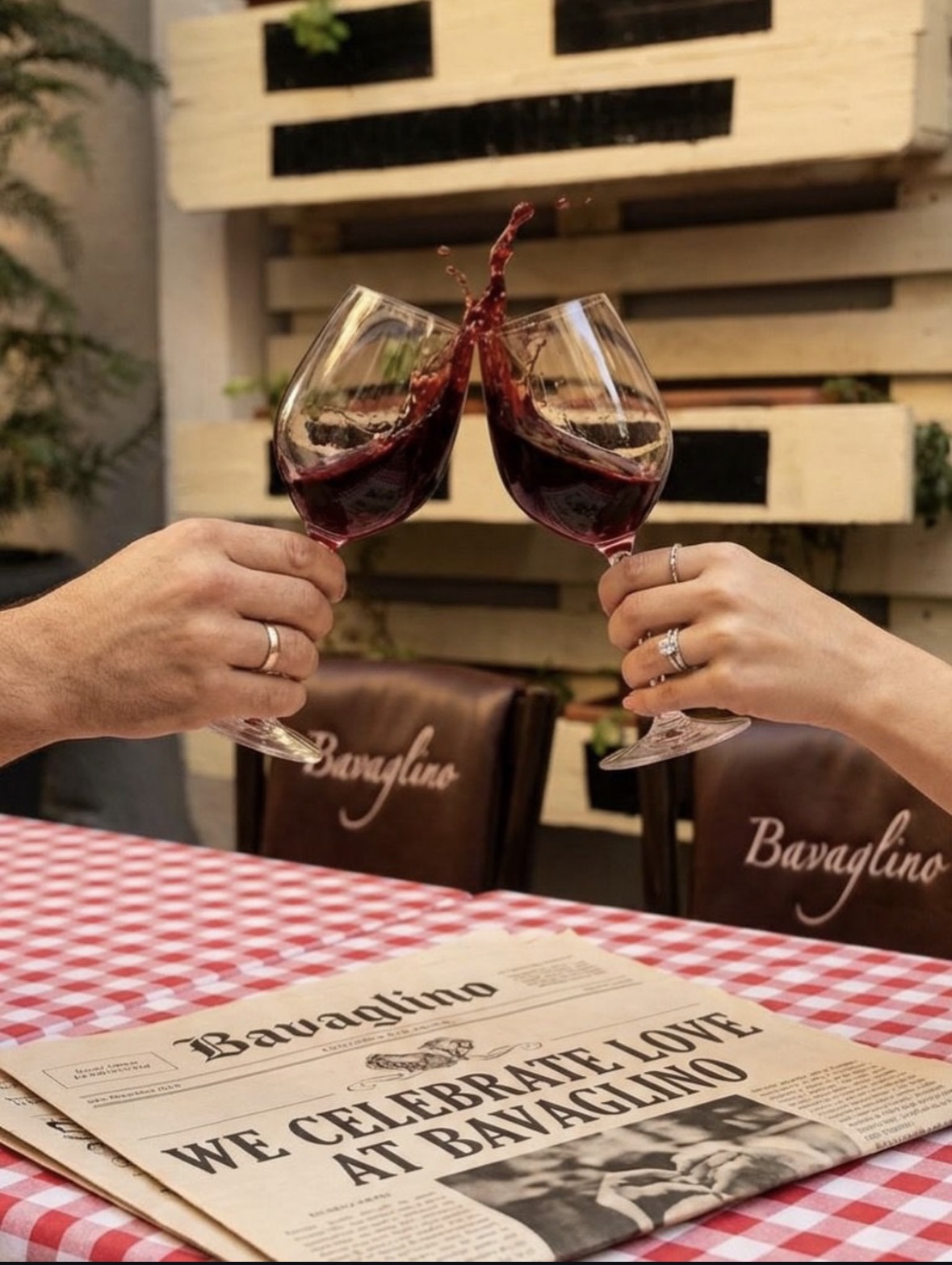 Two glasses of red wine toasting over a red gingham tablecloth at Bavaglino
